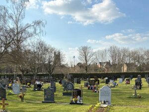 A cemetery with various headstones under a clear blue sky.