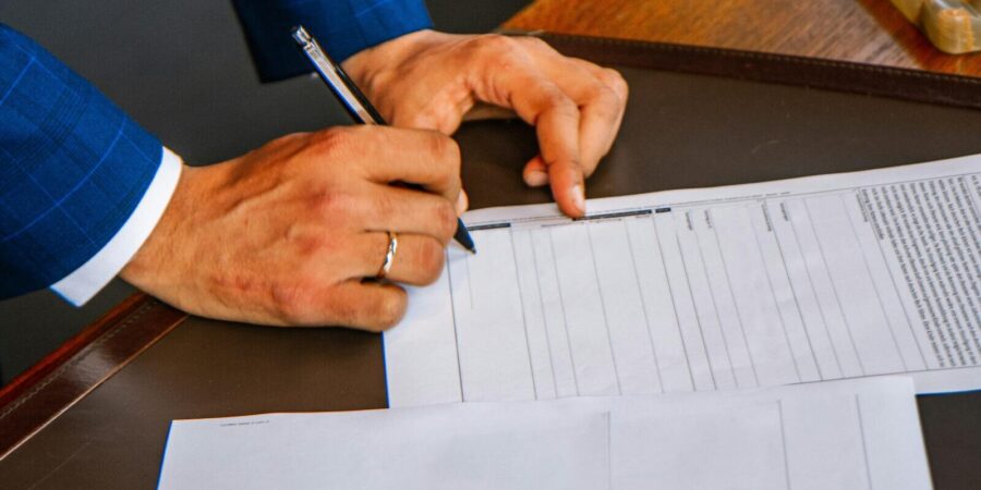 a close-up of a person signing a document on a desk