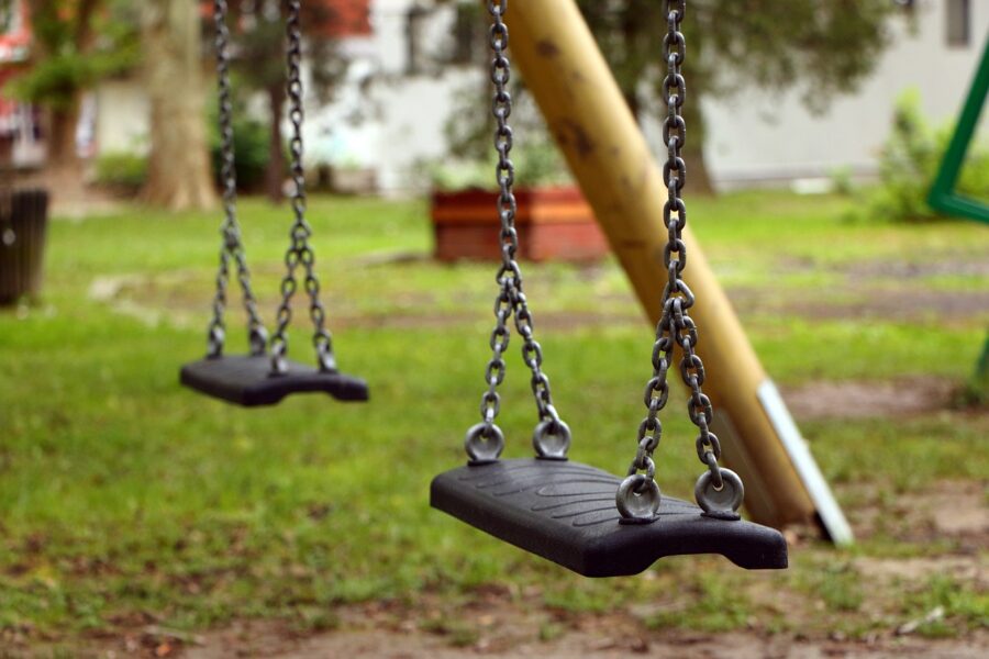 Two empty black swings hang from chains